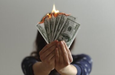 Apps like Dave and EarnIn: hands holding burning dollar bills showing the real cost of cash advances