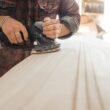 acamento — craftsman sanding a wood surface during the finishing stage